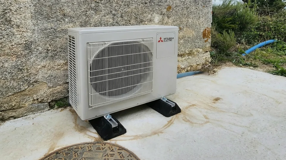 Technicien en salopette bleue effectuant la maintenance d'un climatiseur mural split dans un salon moderne